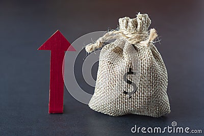 Boost or increase your income with directional arrow, money and a bag over dark background. Financial concept. Copy space Stock Photo