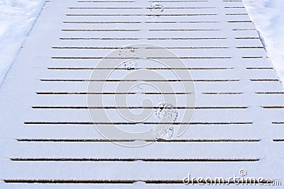 Boot prints left in the snow on a wooden path Stock Photo