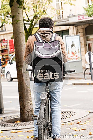 Uber eats man on bike delivery with logo sign brand backpack Ubereats deliver from Editorial Stock Photo