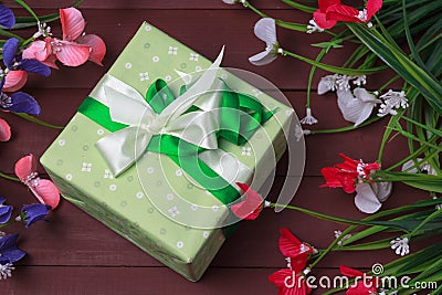 Border of flowers with Mother`s Day gift box and tag against a rustic wood background Stock Photo