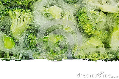 Border of fresh frozen green broccoli in ice closeup on white background. Stock Photo