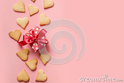 Border of homemade heart shaped cookies and gift on pink. Space for text Stock Photo