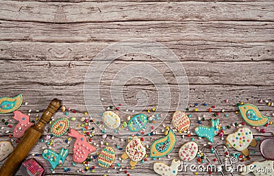 The border is made of homemade cookies and a scattering of colored chocolate eggs on a wooden background. Stock Photo