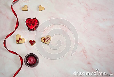 The border is made of silk ribbon, gift box, candle in a glass candlestick and homemade cookies in the shape of a heart on a pink Stock Photo