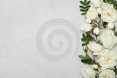 Border of white rose flowers and green leaves on light gray background from above, beautiful floral pattern, flat lay Stock Photo