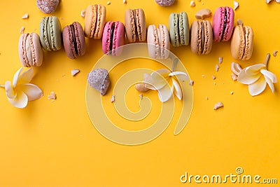 Bordure of delicious macarons with pieces of nuts on yellow background. Stock Photo