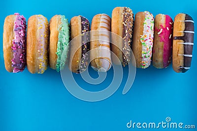 Bordure of different kinds of donuts on blue background with copy space. Stock Photo