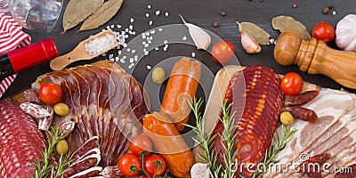 Bordure of different spanish embutidos, like fuet, jamon, chorizo, bacon and lomo embuchado with red wine, olives and spice. Stock Photo