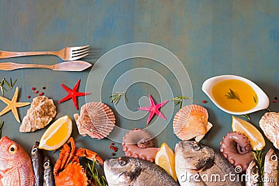 Bordure of raw fresh fish variety and sea stars on blue wooden background with copy space. Stock Photo