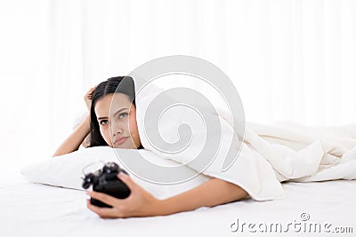 Bored Asian woman hates getting stressed waking up early morning on bed,Alarm clock Stock Photo