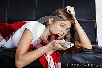 Bored beautiful girl watching tv, lying on sofa at home. Stock Photo