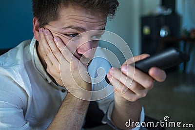 Bored caucasian man watching tv and zapping sitting on a couch at home or hotel. Stock Photo