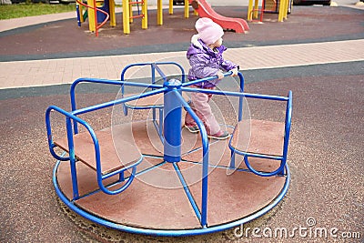 bored child on a carousel on a playground on an autumn sunny day. Stock Photo