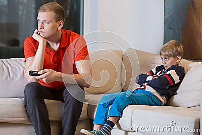 Bored child and father is watching TV Stock Photo