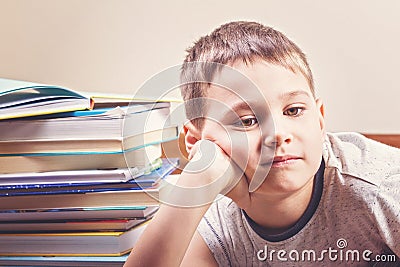 Bored child between piles of books Stock Photo