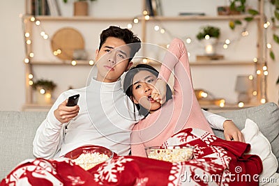 Bored Chinese Couple Watching TV Yawning Celebrating Christmas At Home Stock Photo