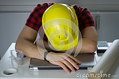 Bored construction Worker is lying on a laptop Stock Photo