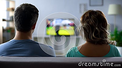 Bored couple watching football match on tv, conflict, passive pastime together Stock Photo