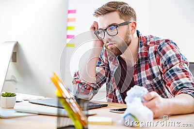 Bored exhausted man sitting on workplace and looking at monitor Stock Photo