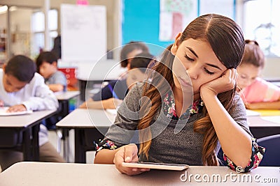 Bored girl reading tablet in elementary school class Stock Photo