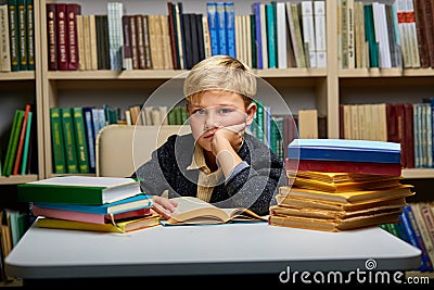 bored caucasian little boy tired of learning doing homework reading book Stock Photo