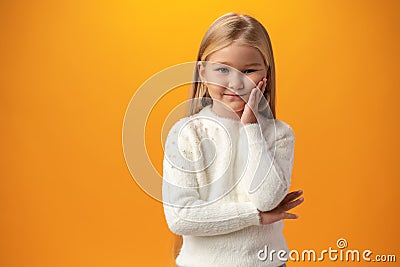 Bored little girl being lonely against yellow background Stock Photo