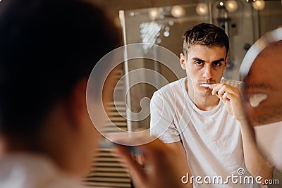 Bored man brushing teeth,sad,tired.Occupational burnout syndrome.Chronic stress.Depressed single man.Lazy with personal hygiene Stock Photo