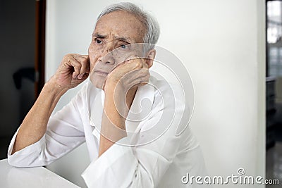 Bored senior woman is propped her cheeks with hands,sad facial expression,spending home alone,asian elderly people thinking having Stock Photo