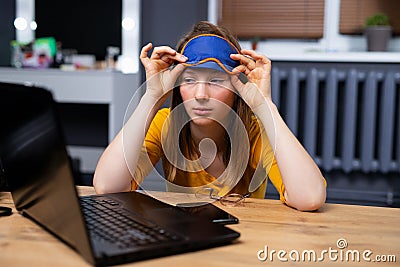 Bored sleepy young woman sit at home office table look in distance unable to work at laptop, exhausted girl student feel Stock Photo