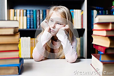 Bored and tired schoolgirl studying with a pile of books Stock Photo