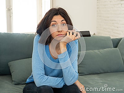 Bored woman changing TV channels with remote control Stock Photo