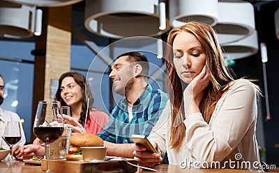 Bored woman messaging on smartphone at restaurant Stock Photo