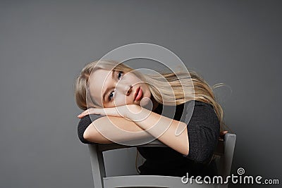 Bored young woman sitting astride on chair with head resting on backrest Stock Photo