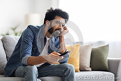 Boring Show. Portrait Of Upset Young Indian Guy Watching TV At Home, Stock Photo