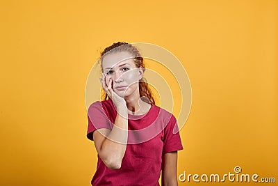 Boring young lady in red shirt keeping hand on chin, thinking about issue Stock Photo