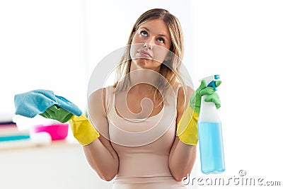 Boring young woman holding a duster and spray at home. Stock Photo