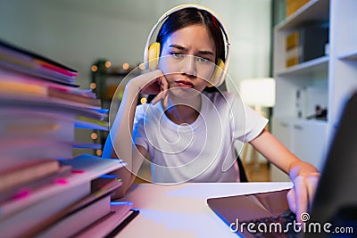 Boring young woman wearing headset and hand typing on keyboard with document file on the table, working on computer. Stock Photo