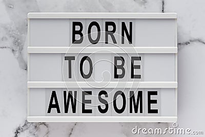 `Born to be awesome` words on a lightbox on a marble background, top view. Overhead, from above, flat lay Stock Photo