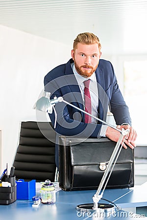 Boss at desk leaning over briefcase Stock Photo