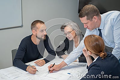 The boss gives instructions to three employees in the office conference room. Brainstorming engineers and architects. Stock Photo