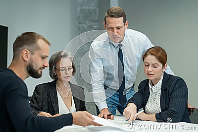 The boss gives instructions to three employees in the office conference room. Brainstorming engineers and architects. Stock Photo