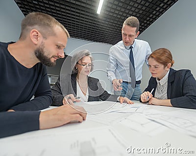 The boss gives instructions to three employees in the office conference room. Brainstorming engineers and architects. Stock Photo