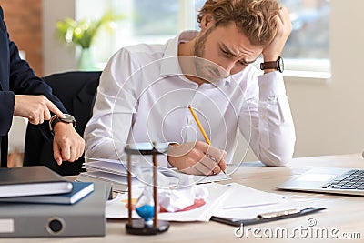 Boss reminding young man of duration in office Stock Photo