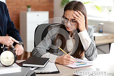 Boss reminding young woman of duration in office Stock Photo