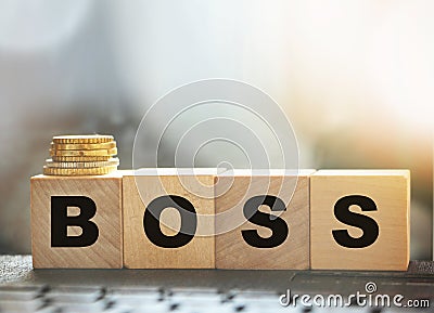 The boss sign on a wooden cubes standing on computer keyboard and stack of coins. CEO business management concept Stock Photo