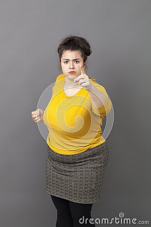 Bossy 20s fat woman showing her index and fist to denounce Stock Photo