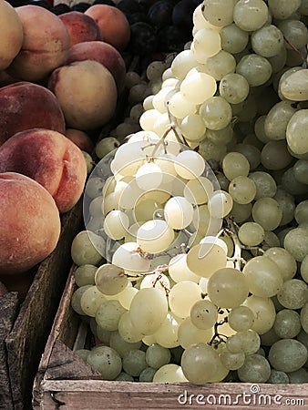 Yummy Grapes bask in the sun next to a box of juicy peaches Stock Photo