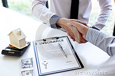 Both businessmen shake hand to congratulate them on their successful signing of a contract with a home insurance agent Stock Photo