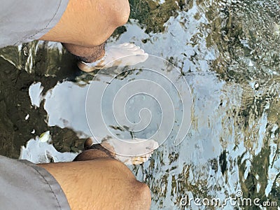 both feet submerged in clear water Stock Photo