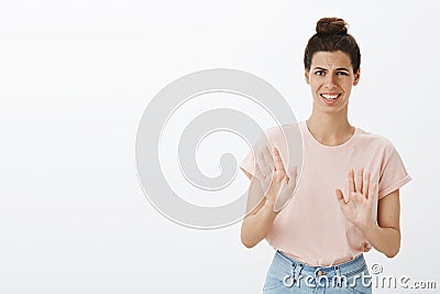 Bothered polite young female coworker rejecting creepy and disgusting offer looking intense and awkward waving palms in Stock Photo